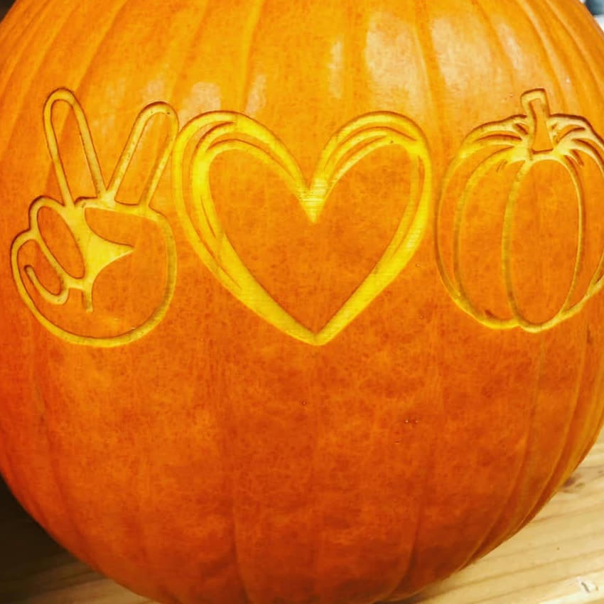 A pumpkin laser-engraved with a peace sign, a heart, and a pumpkin